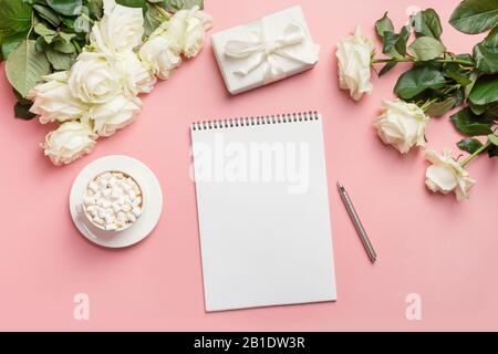 Leere leere leere und weiße Rosen auf pinkfarbenem Hintergrund. Draufsicht mit Kopierbereich. Romantischer Brief oder Checkliste. Hochzeitsplanung. Stockfoto