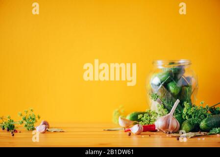 Zutaten, Gewürze und Kräuter für Konservengurken auf gelbem Hintergrund. Kopierbereich. Dill Blumen, Lorbeerblatt, Meerrettichblatt, Knoblauch, Gherkins Stockfoto