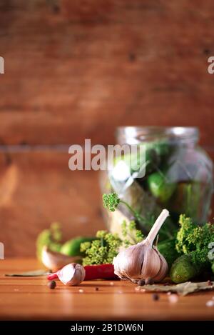 Gurken in Dosen beizen. Zutaten für marinierte Gherkins, Glasbecher, Knoblauch, Dill, Salz, Pfeffer auf grünem Hintergrund. Kopierbereich. Konzept der Gemüsekonservierung Stockfoto