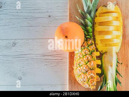 Ananas- und Orangenscheiben auf Holzhintergrund. Tropische Früchte. Gesundes Lebensmittelkonzept. Draufsicht und Kopierbereich. Stockfoto