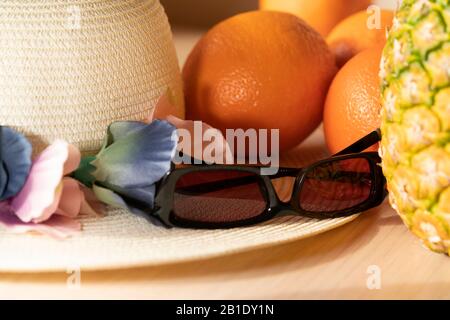 Stillleben von Strohhut, tropischen Früchten und Sonnenbrillen symbolisieren Reisen in warme Länder an die Küste. Farbbild, Reisekonzept. Stockfoto