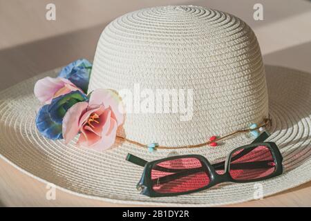 Sonneneinschätzung und Strohhut symbolisieren Ferien und Reisen in warme Länder. Farbbild mit Kopierbereich. Stockfoto