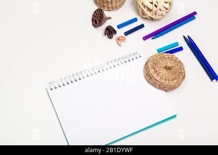 Leere Seite des Spiralnotizblocks auf weißem Tisch. Crayon-Bleistift und Stift - flaches Laienfoto. Stockfoto