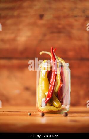 Probiotika Lebensmittel Hintergrund. Eingepickte heiße Paprikaschoten in Glasgefäßen auf weißem Holzhintergrund. Kopierbereich. Stockfoto