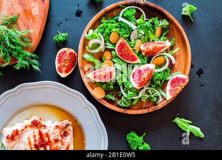 Herbst Salat von Rucola, Feigen in braunem Steingut Teller auf einem dunklen Hintergrund. top View Stockfoto