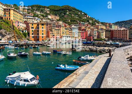 Boote ankerten am Pier als bunte Häuser vor dem Hintergrund in der Kleinstadt Camogli in Ligurien, Italien. Stockfoto