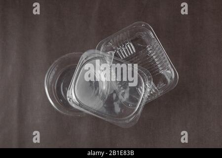 Leere Plastikbehälter auf dunkelbraunem Grund Stockfoto