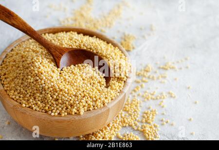 Roher trockener Hirse in einer Holzschale mit einem Löffel mit einem Kopierraum Stockfoto