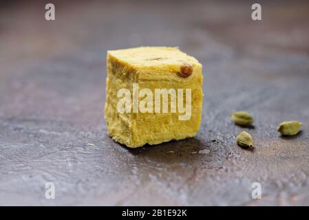 Ein Würfel aus süßen Seifenpapdi- und Kardamomkörnern auf einer Betonküche. Stockfoto