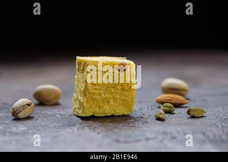 Ein Würfel aus Dessert soan Papdi, Kardamomkörnern, Pistazien und Mandel auf einer betonierten Küchenoberfläche. Stockfoto