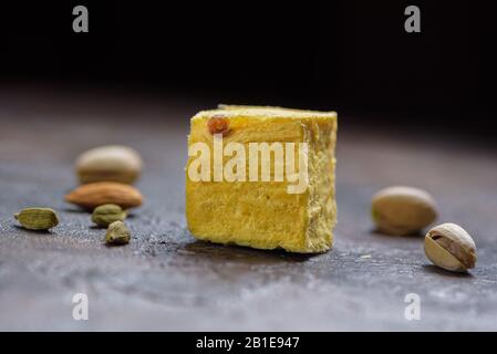 Ein Würfel aus Dessert soan Papdi, Kardamom Körner, Pistazien und Mandel auf Beton Küchenoberfläche. Stockfoto