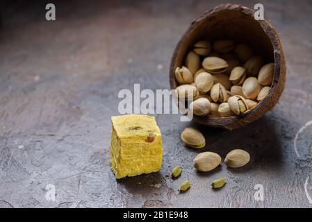 Ein Würfel Dessert Seifenpapdi, Kardamomkörner und Pistazien auf Betonküche Arbeitsplatte. Stockfoto