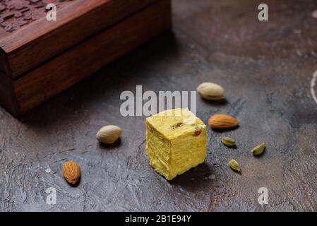 Ein Würfel aus Dessert soan Papdi, Kardamom Körner, Pistazien und Mandel auf Beton Küchenoberfläche. Stockfoto