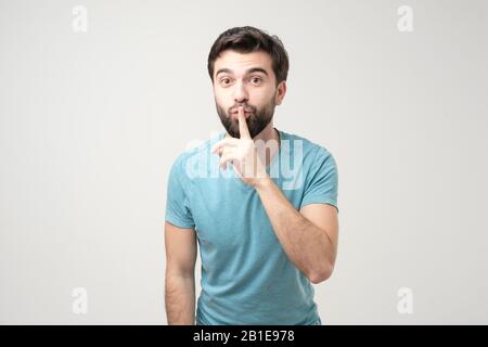 Der ernsthaft gut aussehende Mann hält den Finger auf den Lippen, versucht, die Verschwörung zu halten. Shh, bitte zum Schweigen bringen. Stockfoto