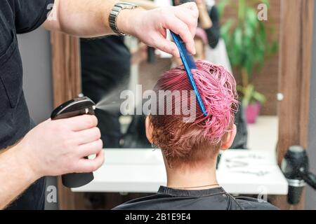 Friseursalon oder barber streut Wasser auf die Haare des Kunden. Stockfoto