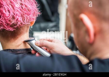 Nahaufnahme des Friseursalons rasiert Frauenhaare mit elektrischem Rasierer im Schönheitssalon. Stockfoto