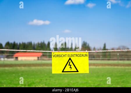 Elektrifizierter Zaun mit gelbem Warnschild VORLICHT ELEKTOZAUN (Elektrischer Gefahrenzaun) Stockfoto