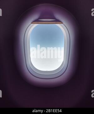 Schöner Hintergrund des Flugzeugfensters. Windows ist ein Fliegenflugzeug zum Fliegen in blauem Himmel bei dichtem Nebel. Stockfoto