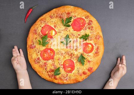 Kinder halten in der Nähe der großen margarita Pizza mit Käse, Petersilie, gebackenen Tomaten auf Holztisch, flacher Lay Stockfoto