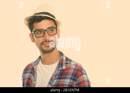 Studio shot der jungen Persischen Mann denken beim Tragen der Brille und Hut Stockfoto