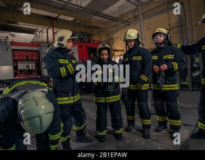 Feuerwehrleute vorbereiten für Notdienst. Die feuerwehrleute setzen auf Handschuhe. Stockfoto