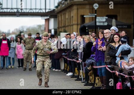 Windsor, Großbritannien. Februar 2020. Ein Soldat der 1st Battalion Welsh Guards zieht einen Muskel, als er am Dienstag in Shrove in der Windsor and Eton Flippin' Pancake Challenge um Hilfe des Alexander Devine Children's Hospice Service konkurriert. Credit: Mark Kerrison/Alamy Live News Stockfoto