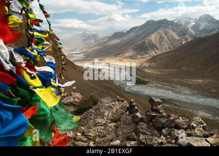 Der Fluss Spiti fließt durch das Tal der Spiti, das von den hohen Gipfeln des Himalayas und den buddhistischen Gebetflaggen an einem schönen Sommertag in der Nähe von Kaza, Indien, flankiert wird. Stockfoto