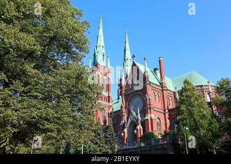 Berühmter gotisch-roter historischer Architekturstein in Helsinki, Finnland mit blauem Himmel und lebendigem grünem Gras. Reisefotografie in der Stadt Europa Stockfoto