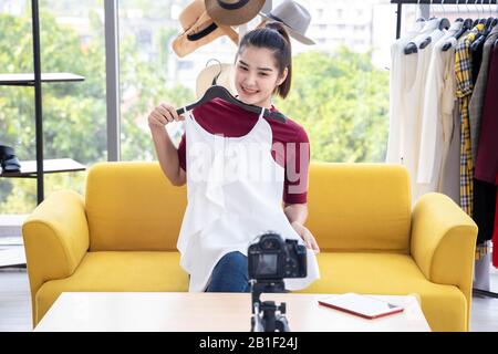 Happy Asian Internet Influencer überprüfen oder verkaufen weiße Kleider per Online-Streaming. Stockfoto