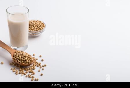 Sojamilch aus Glas, Bohnen in der Schüssel und Holzlöffel Stockfoto