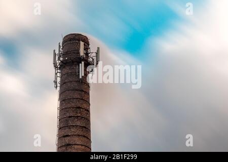 Industrieller Rauch aus dem Kamin am windigen Himmel. Lange Belichtung. Stockfoto