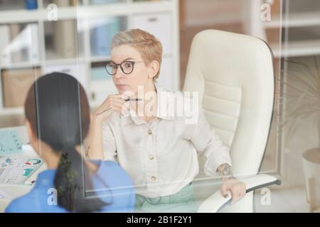 Schockierte Geschäftsfrau, die mit Kollegen im Büro spricht, kopiere Raum Stockfoto