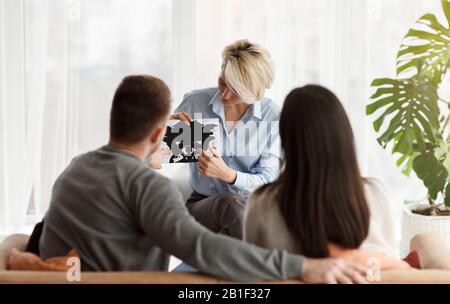 Familienpsychologe Arbeitet Mit Paaren Zusammen, Die Im Büro Ein Inkblot Picture Zeigen Stockfoto