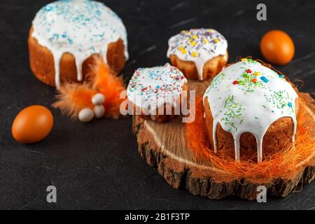 Frischer Osterkuchen, zu Hause gebacken und mit süßem Icing dekoriert. Farbige gekochte Eier liegen als Bestandteil des Osterfeiertags auf dem Tisch. Künstlich Stockfoto