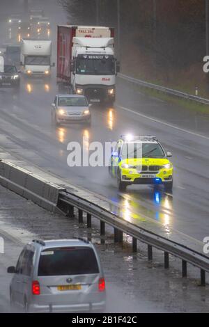 Polizeiauto auf der M6 bei starkem Regenschauer in Chorley, Lancashire. UK Wetter, starker Regen, Hagel-Regenschauer und winterliches Wetter sorgen für schwierige Fahrbedingungen auf der Autobahn M6 in Lancashire. Stockfoto
