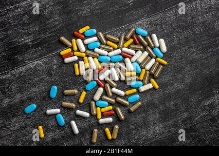 Draufsicht des Herzens von mehrfarbigen medizinischen Kapseln und Pillen auf schwarzem Hintergrund. Das Konzept der Behandlung, Genesung, Medizin, Pharmakologie. Kopie Stockfoto