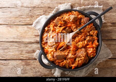 Geschmorter Kohl mit Fleisch, Tomaten, Karotten und Zwiebeln in einer Pfanne auf dem Tisch. Horizontale Draufsicht von oben Stockfoto