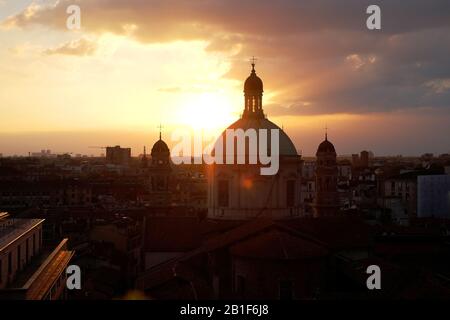 Mailand, Italien, die Skyline der Stadt bei Sonnenaufgang, das Licht bricht durch die Wolken, eine Halbsilhouette Aussicht, die Kirchtuppeln der Chiesa di Sant'Alessandro in Zebedia Stockfoto