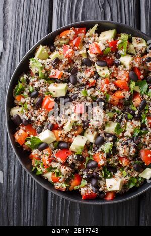 Gekochtes Quinoa mit frischen Avocado, Paprika, Tomaten und schwarzen Bohnen in einem Teller auf dem Tisch. Vertikale Draufsicht von oben Stockfoto
