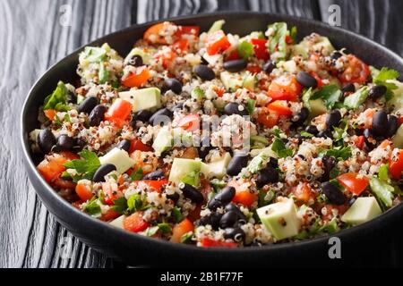 Vegetarischer Quinoa-Salat mit frischen Avocado, Paprika, Tomaten und schwarzen Bohnen in einem Teller auf dem Tisch. Horizontal Stockfoto