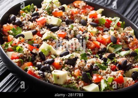 Chinoa im mexikanischen Stil mit frischen Avocado, Paprika, Tomaten und schwarzen Bohnen in einem Teller auf einem Tisch. Horizontal Stockfoto