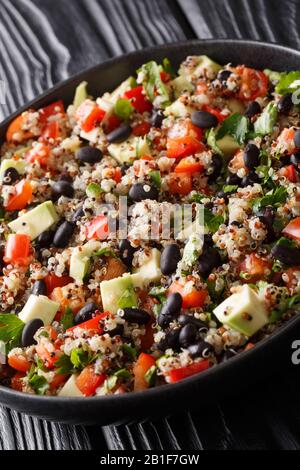 Mexikanischer Chinoa-, Avocado-, Paprika-, Tomaten- und Schwarzbohnen Salat in einem Teller auf dem Tisch. Vertikal Stockfoto