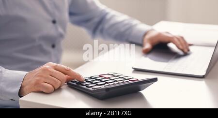 Leitender Mann mit Laptop und Taschenrechner zu Hause Stockfoto