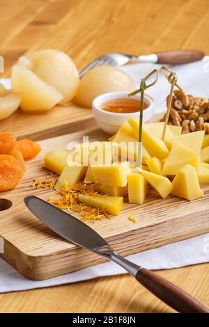 Nahaufnahme der verschiedenen Vorspeisen für Wein - Käse, Walnüsse, getrocknete Aprikosen, Honig und Birne aus der Dose Stockfoto