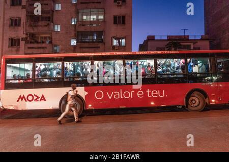 Maputo, Mosambik - 15. Mai 2019: Ein Mann, der am Abend versucht, einen überfüllten Bus zu fangen Stockfoto