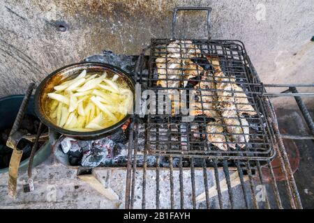 Grillfisch und Pommes Frites auf Holzkohle - einfache Art zu kochen in Mosambik, Afrika Stockfoto