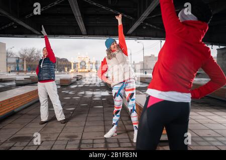 Gesunde Frauen mittleren Alters Erwärmen Sich Und Strecken Ihre Arme in städtischer Umgebung. Trainieren Sie Im Freien Im Park. Aktiver Lebensstil Reifer Frauen. Stockfoto
