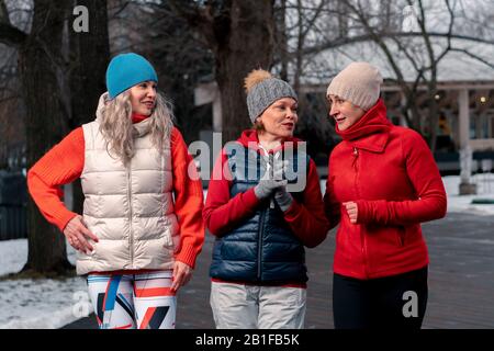 Freunde Reifer Frauen, Die Nach Dem Morgendlichen Lauf Im Park Spazieren Und Über Neuigkeiten Reden. Aktiver Lebensstil Und Freundschaft im Mittelalter. Stockfoto
