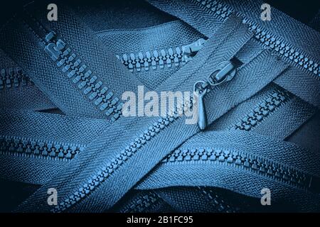 Mehrere Reißverschlüsse in der Nähe, blauer Hintergrund, Textilzubehör. Konzept des Einkaufs, der Fertigung Stockfoto