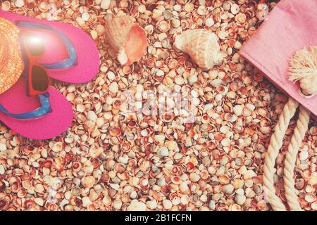 Strandszene. Accessoires für Damen. Sonnenbrille, Flip-Flops-Sandalen und eine Strandtasche, die auf einer Seashell-Schale liegt Stockfoto